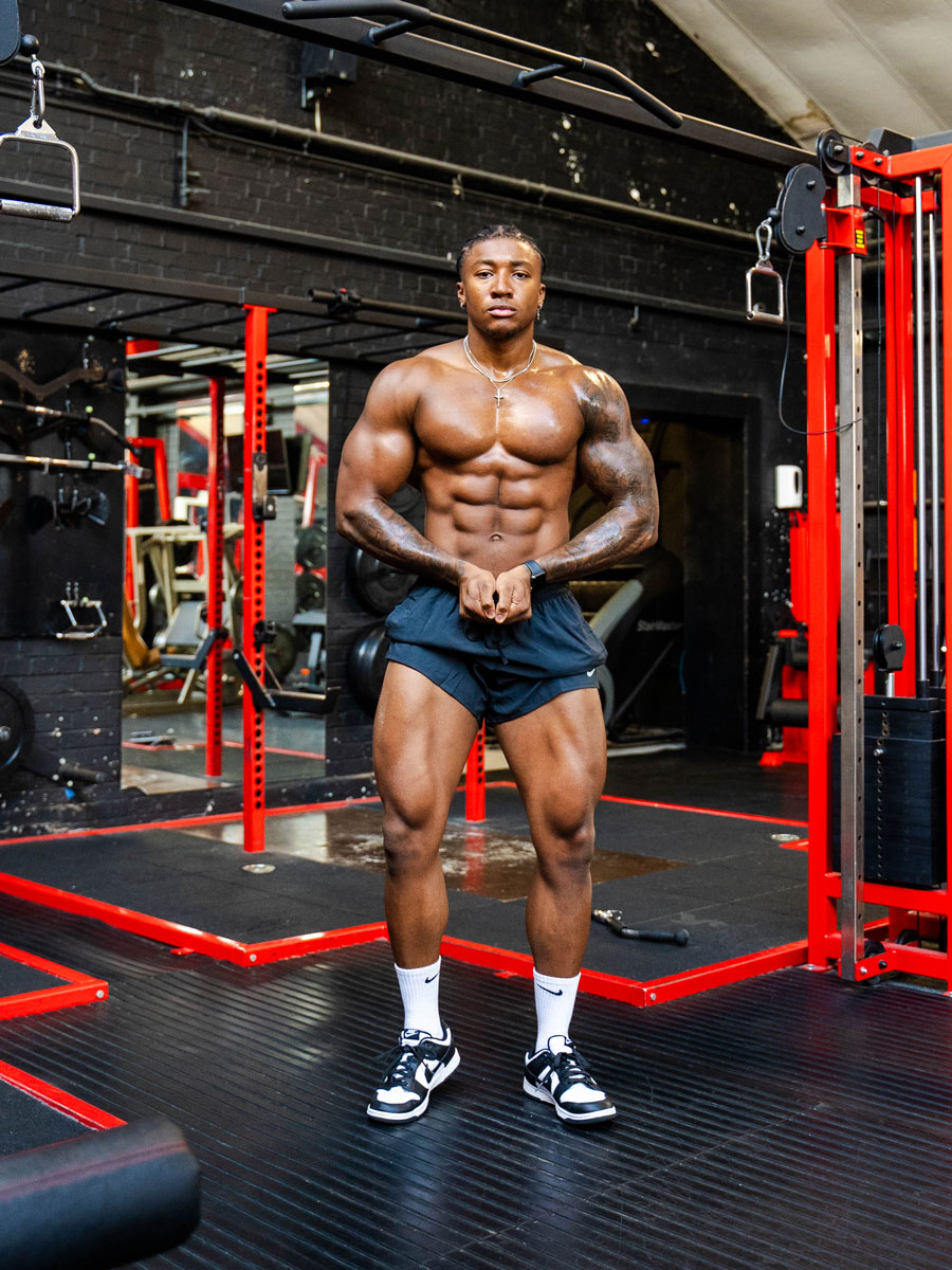 The coach is posing in the gym, flexing his muscular body.